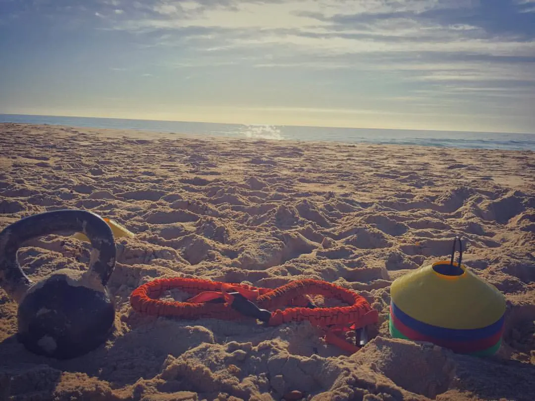 Kettlebell, resistance band and cones set out on the sand